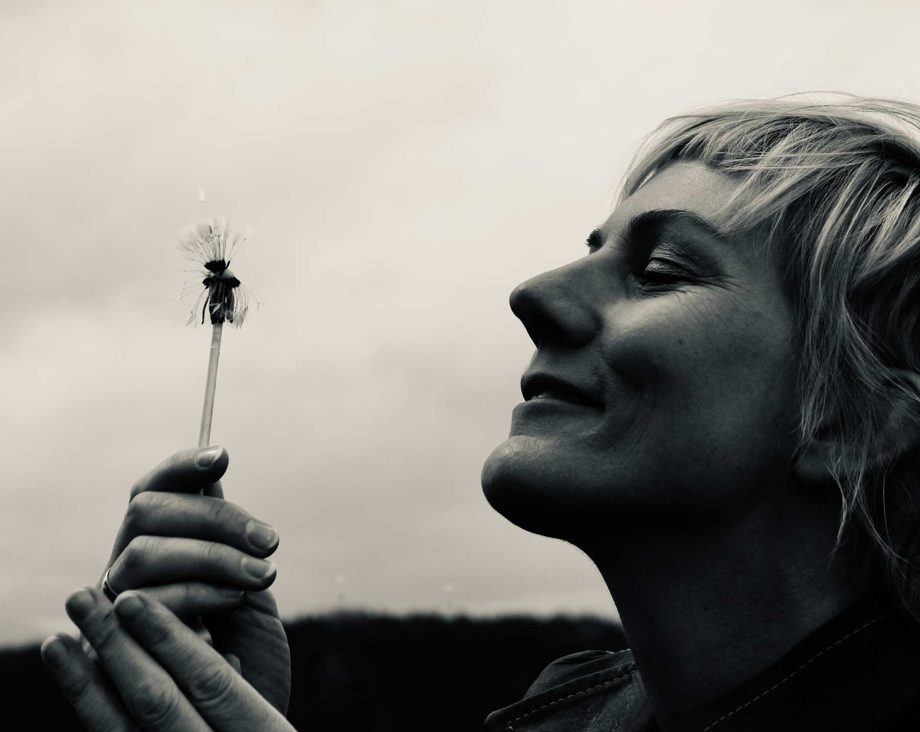 Silvia Jebinger im Profil mit einer verpusteten Pusteblume in den Händen